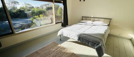Ein Schlafzimmer mit einem Bett, einem Fenster, einer Klimaanlage und einem Teppich.