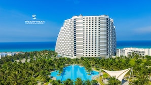 Un hotel moderno con una piscina grande rodeada de palmeras y vistas al océano.