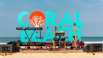 A beach setup with a large sign reading "CORAL BLAST" and musical equipment.