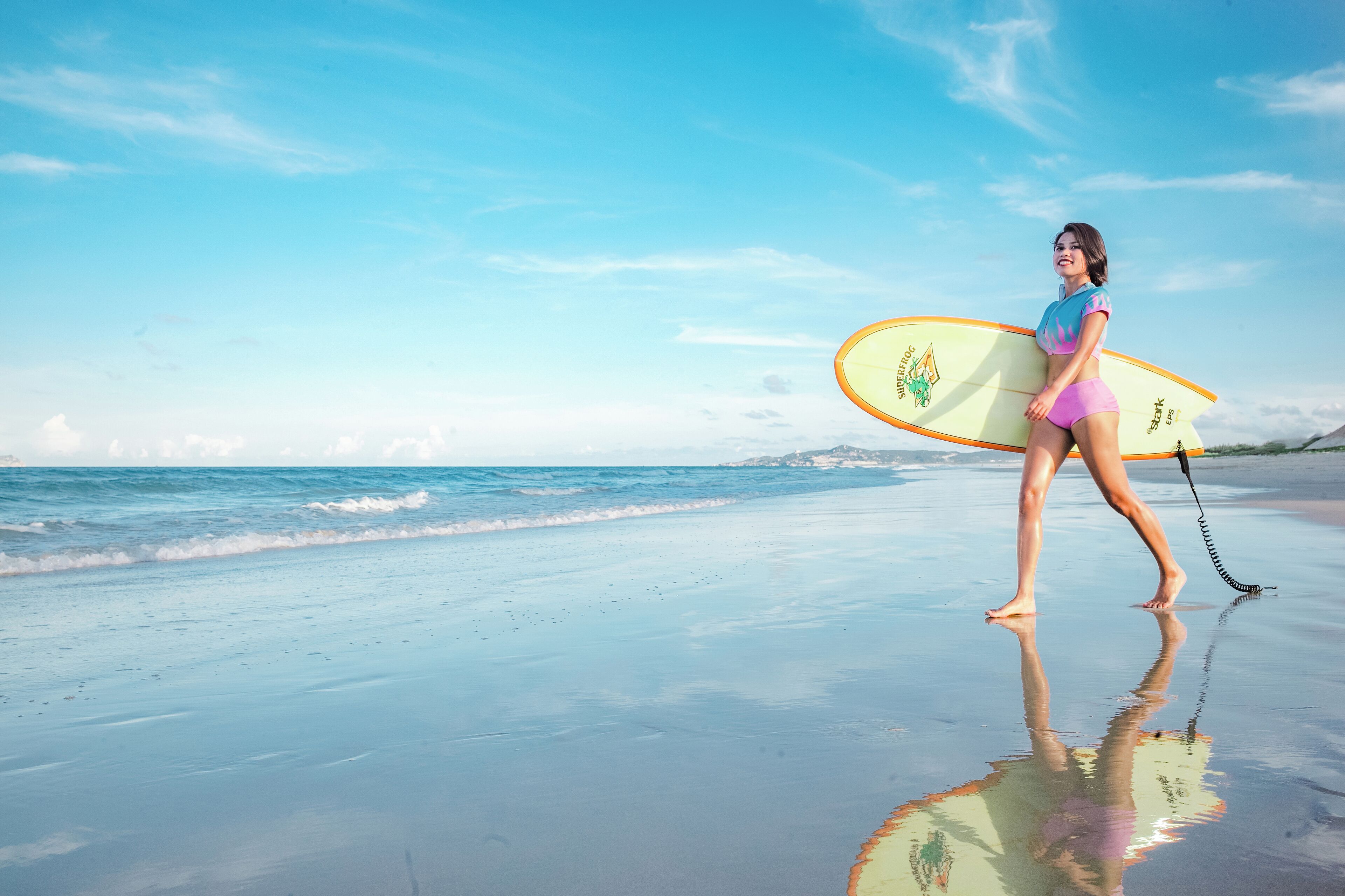 A beach scene with a person carrying a surfboard.