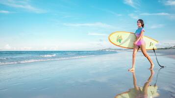 A beach scene with a person carrying a surfboard.