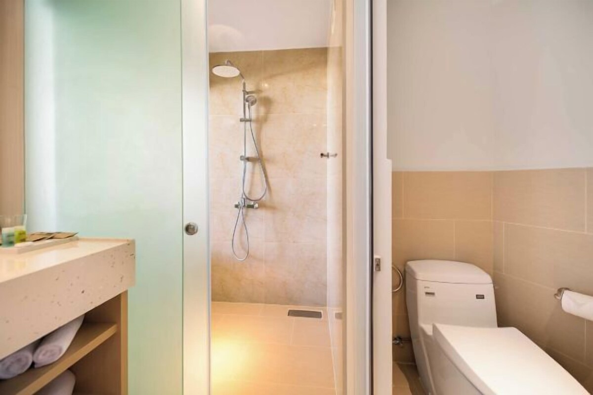 A bathroom with a shower, toilet, and a sink with towels.