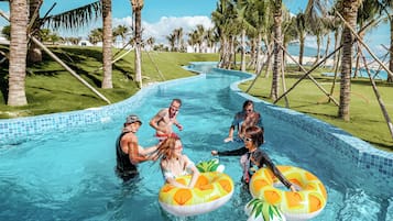 A swimming pool with clear blue water, surrounded by palm trees and a grassy area.