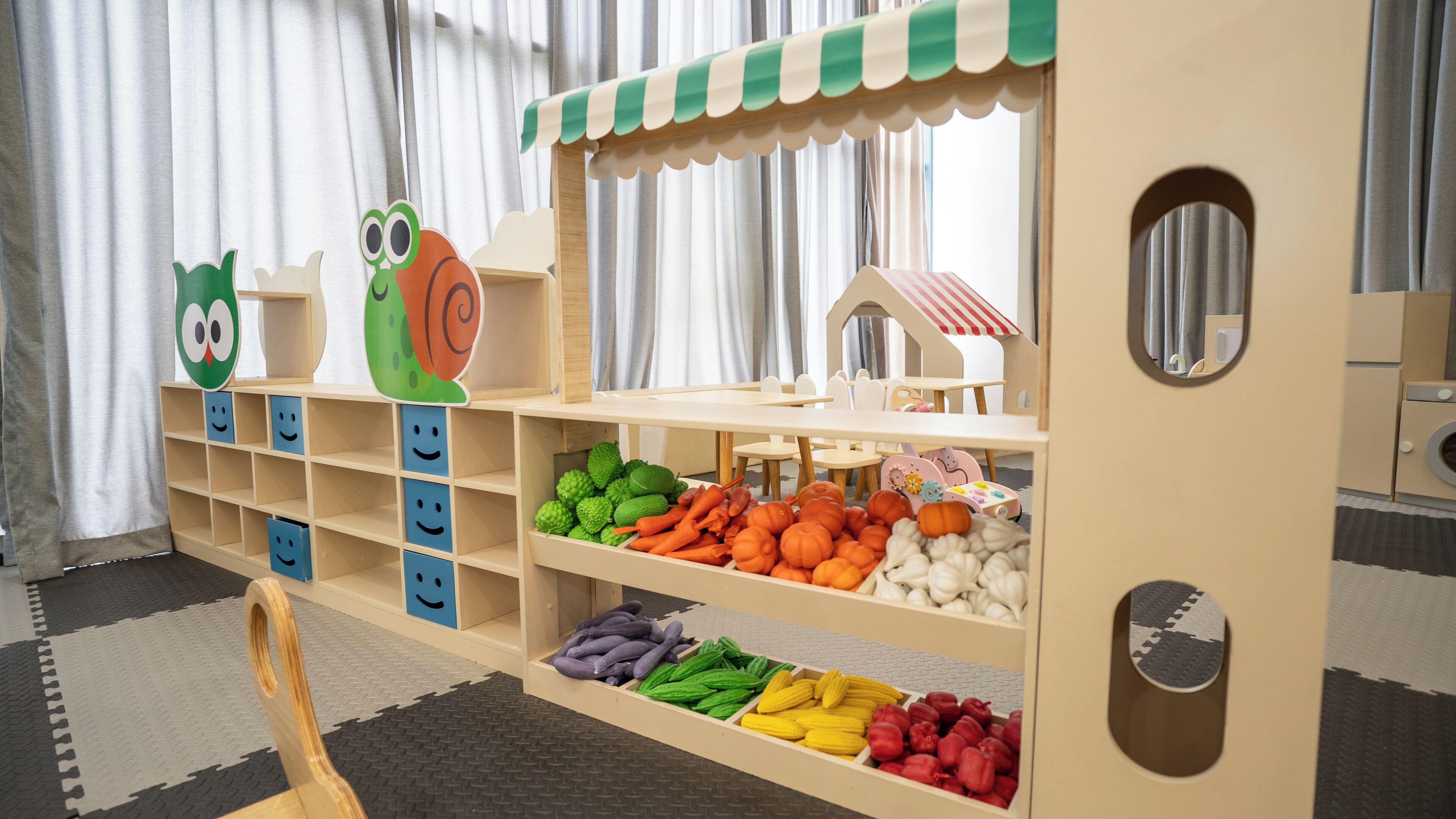 A children's play area with shelves containing various toys and a small playhouse.