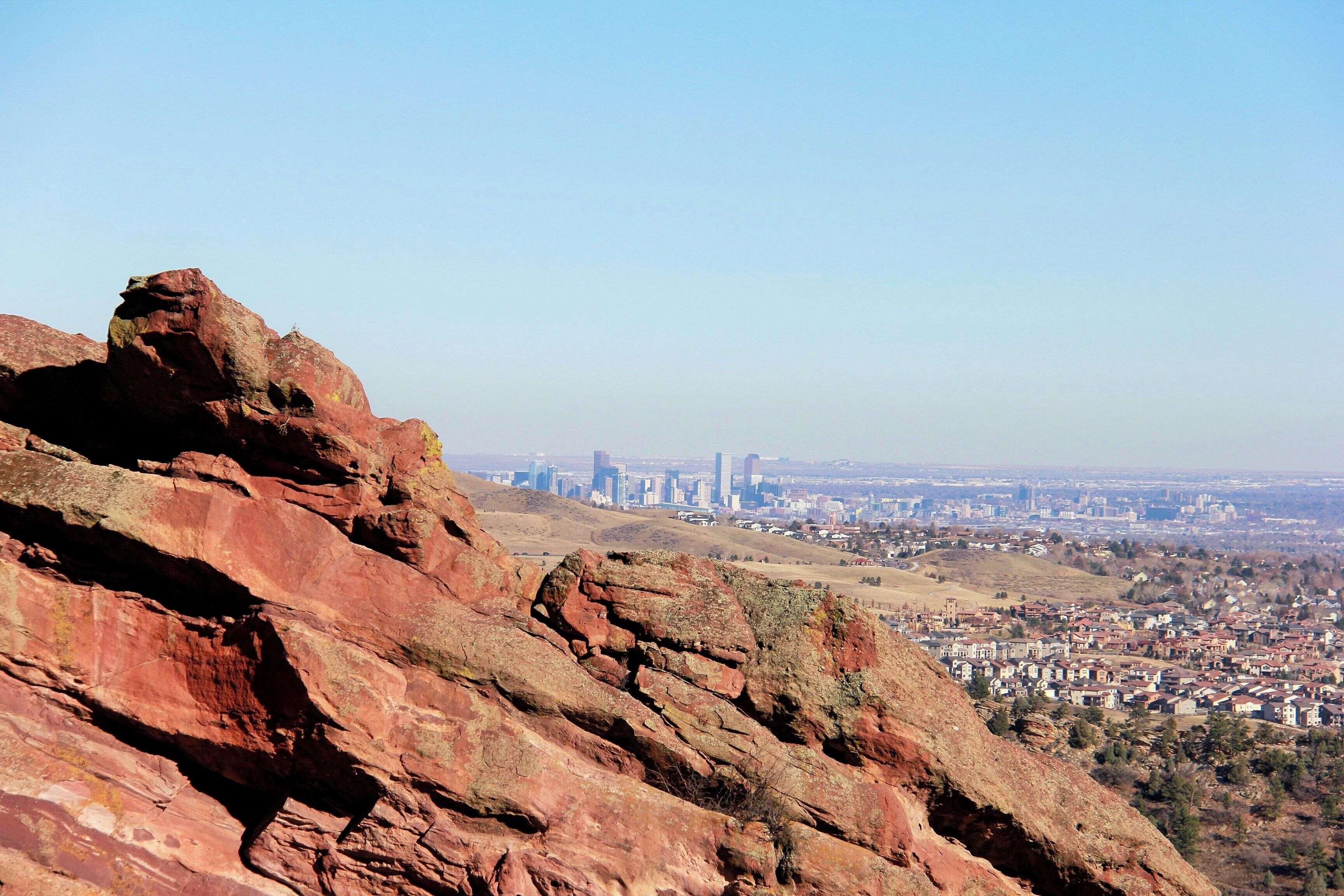 A cityscape with a prominent rocky foreground and a distant view of a city with high-rise buildings.