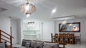 Una sala de estar moderna con sofá, una mesa de comedor de madera y una cocina al fondo.