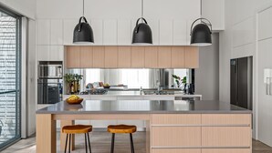 Una cocina moderna con una isla grande, tres lámparas colgantes y armarios de madera.