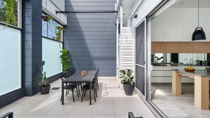 Una cocina moderna con una isla grande, un comedor con mesa y sillas, y un balcón con plantas en macetas.