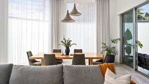 Un comedor moderno con una mesa de madera, sillas tapizadas en gris y lámparas colgantes de mimbre.