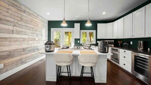 A modern kitchen with a central island, white cabinetry, and a wooden accent wall.