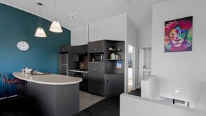 A modern kitchen with a central island, dark cabinetry, and pendant lighting. - Remarkable View 3 bedroom - lake and mountain views (Queenstown)