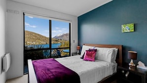 A hotel room with a large window offering a scenic view of a lake and mountains. - Remarkable View 3 bedroom - lake and mountain views (Queenstown)