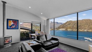 A modern living room with a large window offering a scenic mountain and lake view. - Remarkable View 3 bedroom - lake and mountain views (Queenstown)