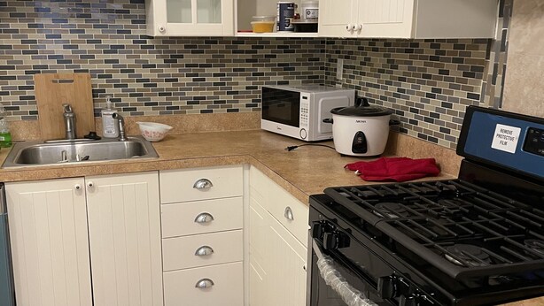 A kitchen with white cabinets, a microwave, a stove, and a tiled backsplash.