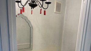 A bathroom with a white sink, toilet, and a chandelier with red candle holders.