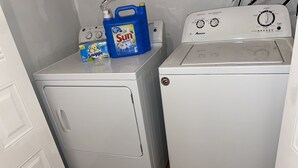 A laundry area with two washing machines, one with a control panel and a detergent bottle on top.