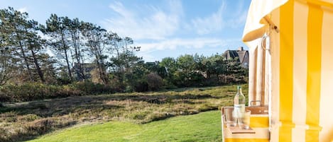 Een terras met gele strepen, een fles Magnus wijn, een glas en een houten bank.