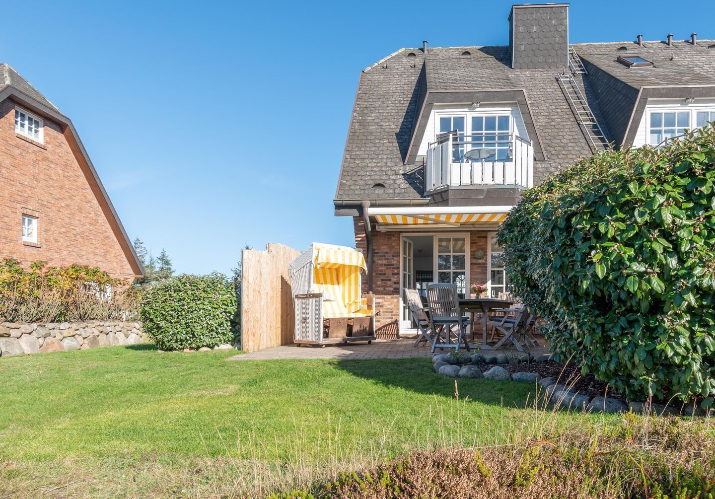 A house with a large backyard, a covered patio with outdoor furniture, and a brick exterior.