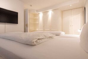 A hotel room with a bed, a TV mounted on the wall, and a wardrobe with multiple doors.