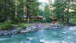 A riverside cabin with a view of a flowing river, surrounded by dense forest.