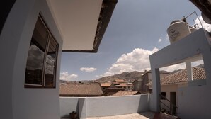 Terraço no telhado com vista para uma cidade e montanhas.