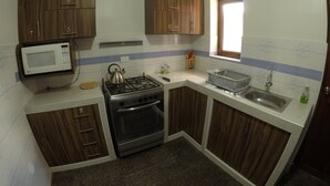 Uma cozinha compacta com armários de madeira, micro-ondas, fogão a gás e pia.