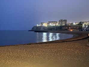 A beach with a curved shoreline, a building with multiple floors in the background, and a clear sky. - Eva's Sea View 2 Bed 2 Bath Parking & NO GUEST FEES (Broadstairs)