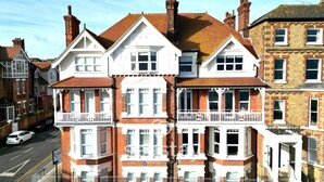 A row of terraced houses with white and red brick facades, bay windows, and a white car parked on the street. - Eva's Sea View 2 Bed 2 Bath Parking & NO GUEST FEES (Broadstairs)