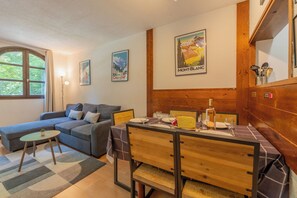 Un salon chaleureux avec un canapé, une table à manger pour deux personnes et une tête de lit en bois.
