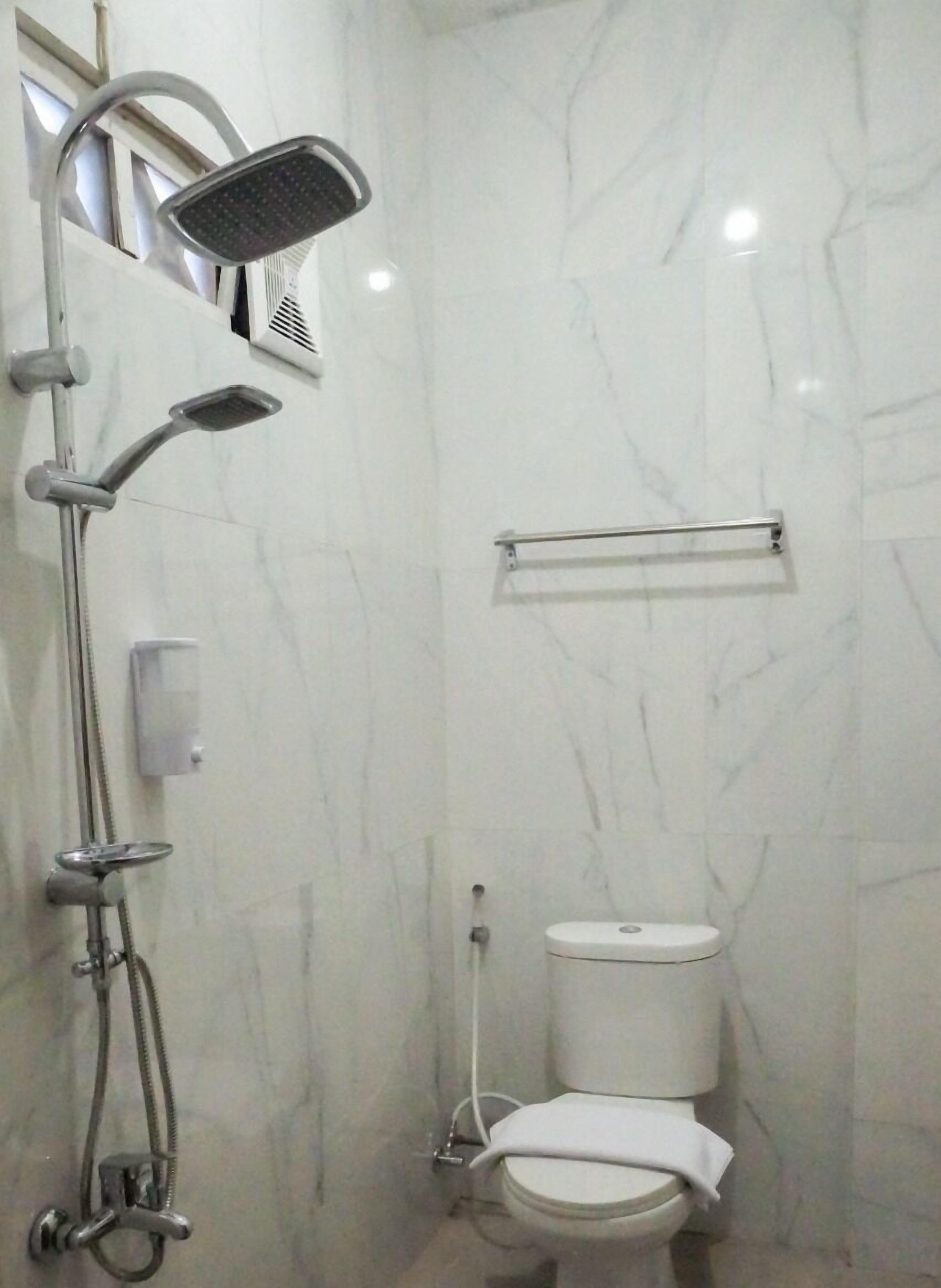 A bathroom with a shower, toilet, and a towel rack.
