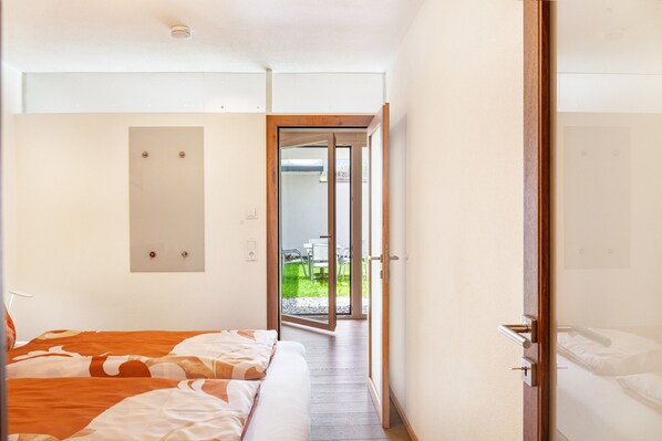A hotel room with a bed, a door leading to a balcony, and a view of the outside. - Apartment "Robi" with Mountain View, Garden & Wi-Fi (Fulpmes)