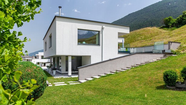 A modern two-story house with a staircase leading to the entrance, surrounded by greenery and a mountainous backdrop. - Apartment "Robi" with Mountain View, Garden & Wi-Fi (Fulpmes)