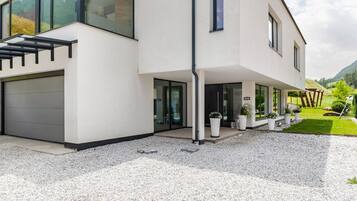 Una casa moderna de dos pisos amb garatge, grans finestres i un carrer d'accés de grava.