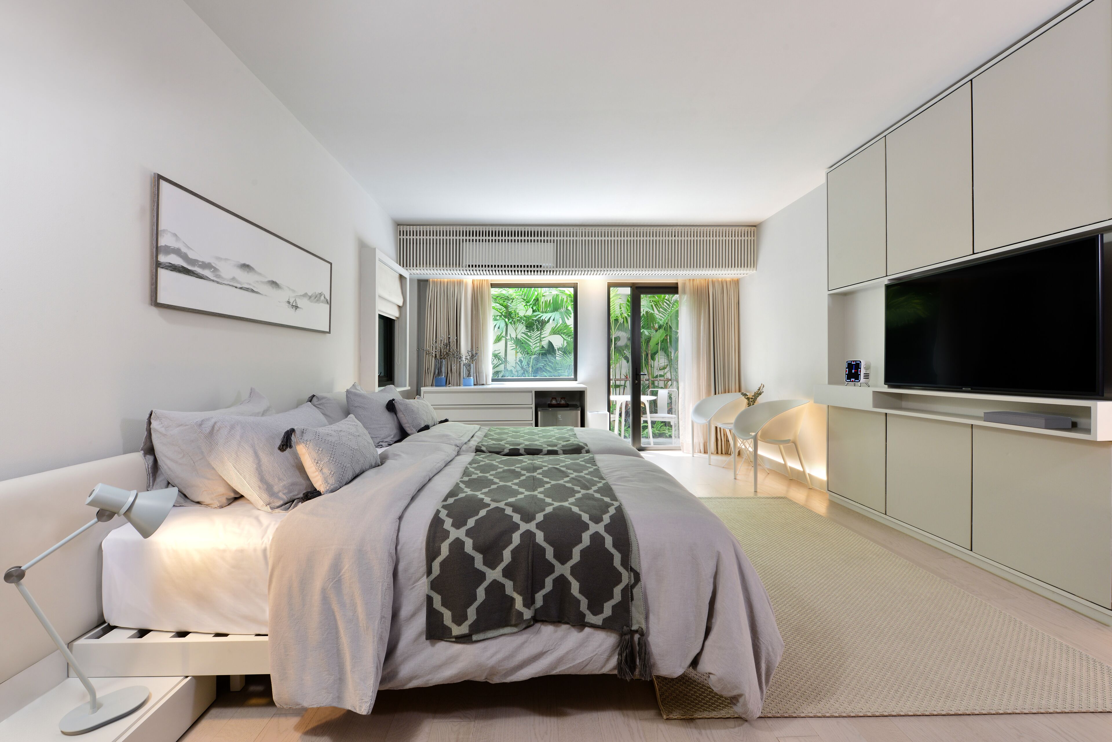 A modern bedroom with a bed, a TV, and a large window.