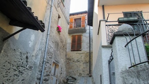 A narrow alleyway with a stone wall on one side and a building with a balcony on the other. - Beautiful apartment for 3 people with A/C, WIFI, TV and balcony (San Siro)