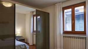 A bedroom with a bed, a nightstand, a mirror, a window with curtains, and a radiator. - Beautiful apartment for 3 people with A/C, WIFI, TV and balcony (San Siro)