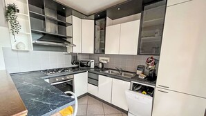 A modern kitchen with a gas stove, microwave, sink, and dishwasher. - Beautiful apartment for 3 people with A/C, WIFI, TV and balcony (San Siro)
