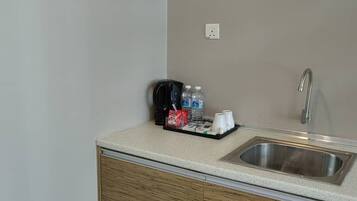 Un angolo cottura dotato di lavello, una macchina da caffè e un vassoio con tazze e bottiglie.