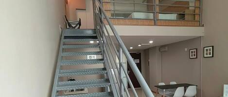 A staircase with metal railings leading to a lofted area with a wooden floor.
