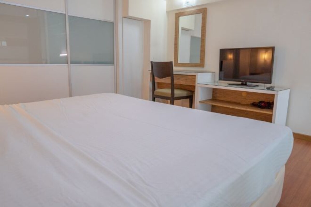 Une chambre d’hôtel comprenant un lit, un bureau avec une chaise, une télévision et un miroir.