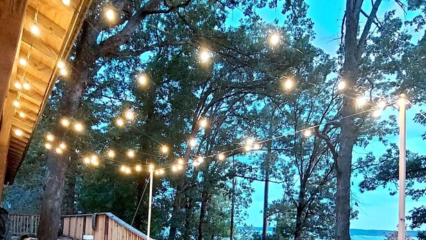 Une terrasse en bois avec des sièges d’extérieur et des guirlandes lumineuses.