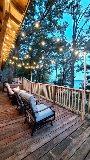 Eine Holzterrasse mit Sitzgelegenheiten und Lichterketten.