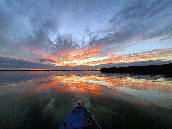 Un lac paisible au coucher du soleil, avec un kayak au premier plan.