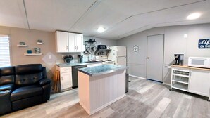 Une cuisine compacte avec des meubles blancs, un îlot central et un four à micro-ondes posé sur un plan de travail en bois.