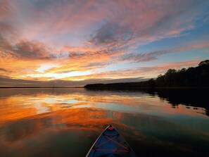 Un lac paisible au coucher du soleil, avec un canoë au premier plan.