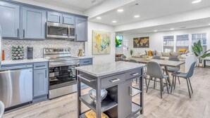 A modern kitchen with grey cabinets, stainless steel appliances, and a central island.