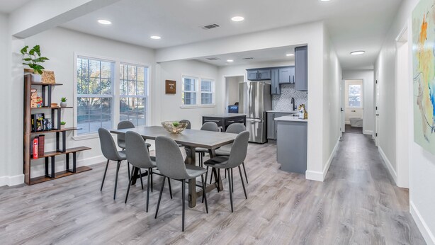 A modern kitchen with a dining area, featuring a large island, built-in appliances, and a view to the outside.