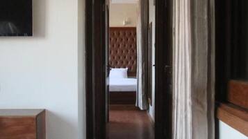 Ein Hotelgang mit einem Bett im Hintergrund, einem Fernseher an der Wand und einem Holzboden.