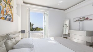 Un dormitorio con cama, cómoda, espejo y vistas al exterior.