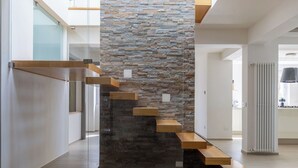 Una escalera moderna con escalones de madera y un muro de piedra.